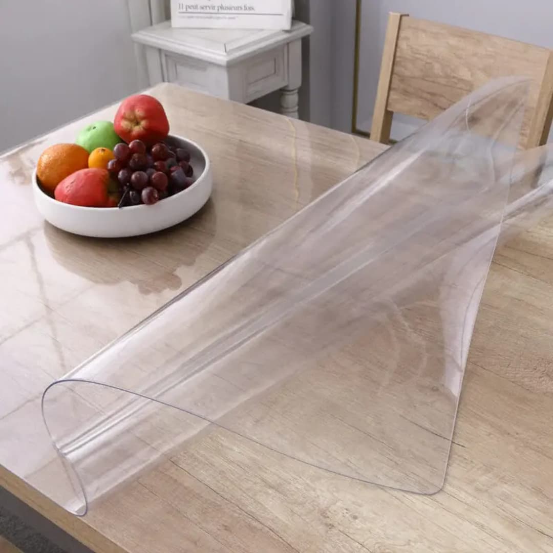 Clear PVC table protector fitted on a table; exact size is stated in the listing