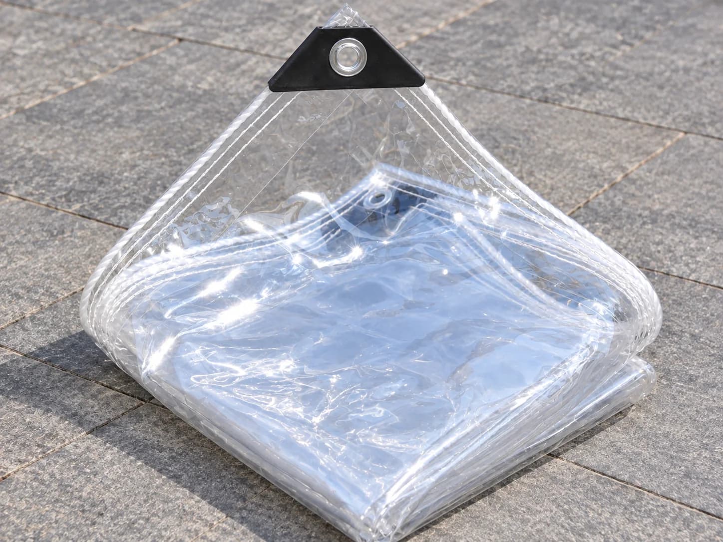 Representative illustration of a folded transparent PVC tarpaulin product; exact thickness and sheet dimensions are stated in the product listing